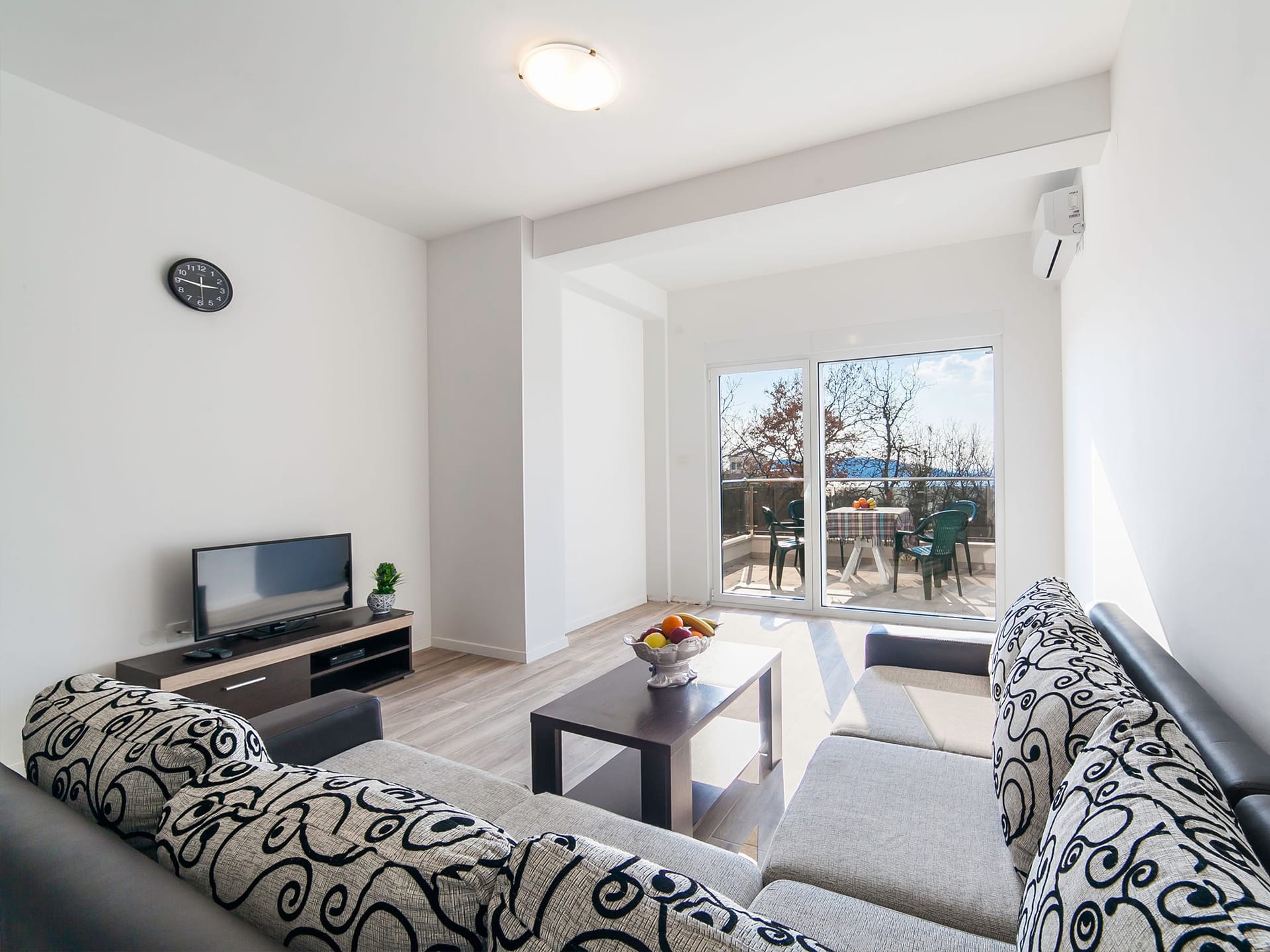 Bright living room with a sofa and access to the terrace in an apartment in Becici, Montenegro. Modern interior with furniture.