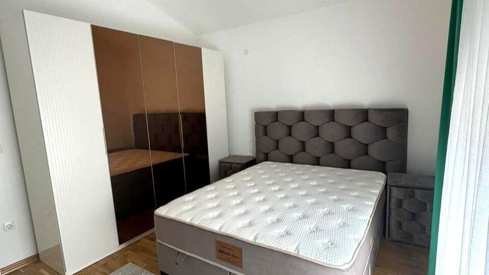 Spavaća soba u stanu u Tivtu, Crna Gora: bračni krevet sa mekanim uzglavljem i ormar sa ogledalskim frontovima.