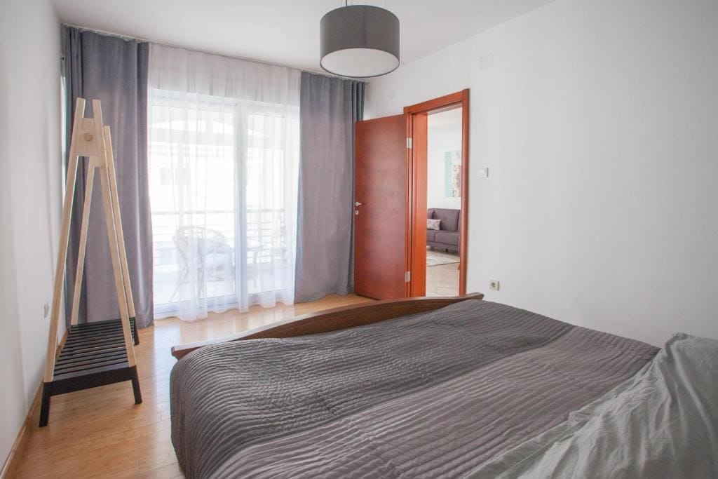 Svetla spavaća soba sa bračnim krevetom i izlazom na balkon u stanu, Budva, Crna Gora. Moderan enterijer.