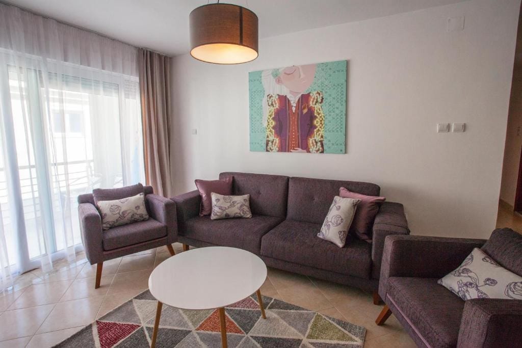 Udobna dnevna soba s mekim nameštajem i izlazom na balkon u stanu u Budvi, Crna Gora. Moderan enterijer.