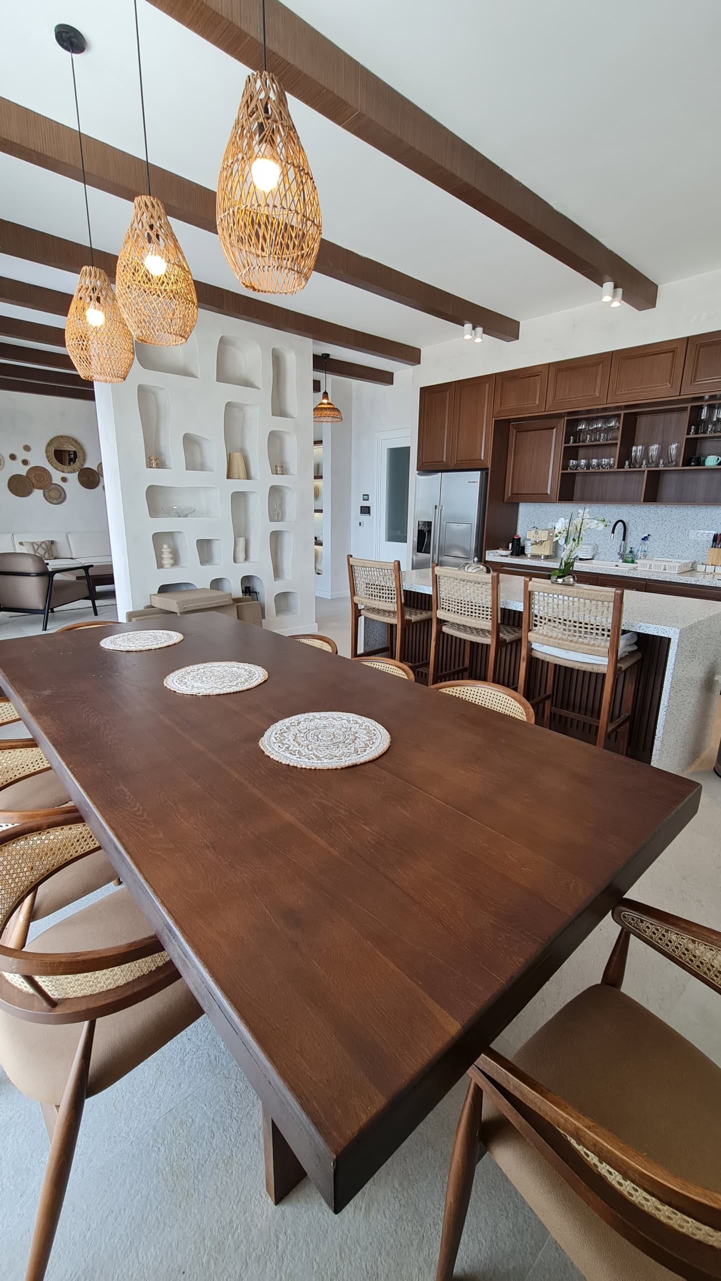 Living room interior with dining area in a villa in Budva, Montenegro: wooden table, wicker chairs, and boho-style decor.