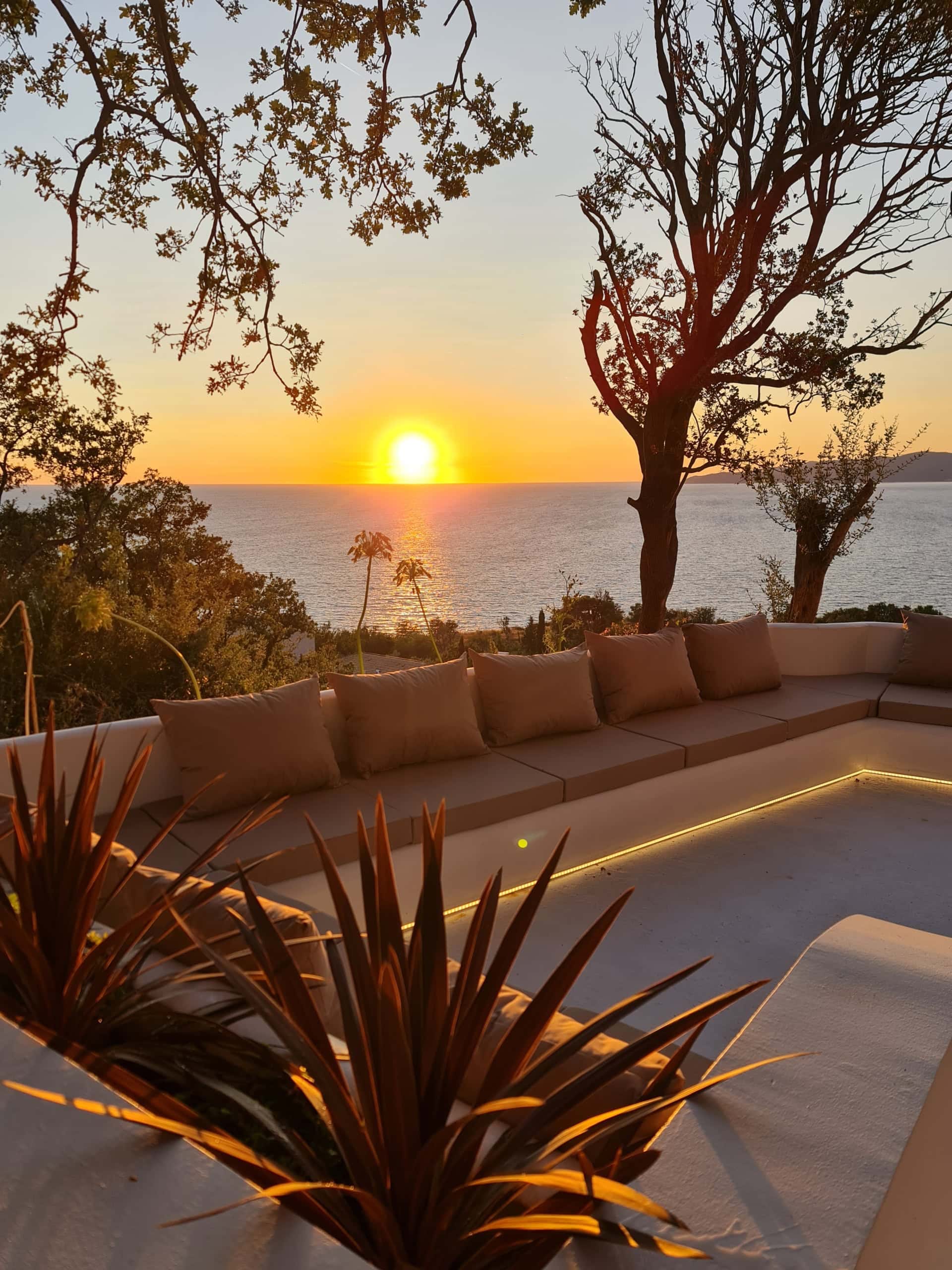 Villa terrace in Budva, Montenegro: a lounge area with soft sofas, lighting, and a panoramic view of the sunset over the sea.