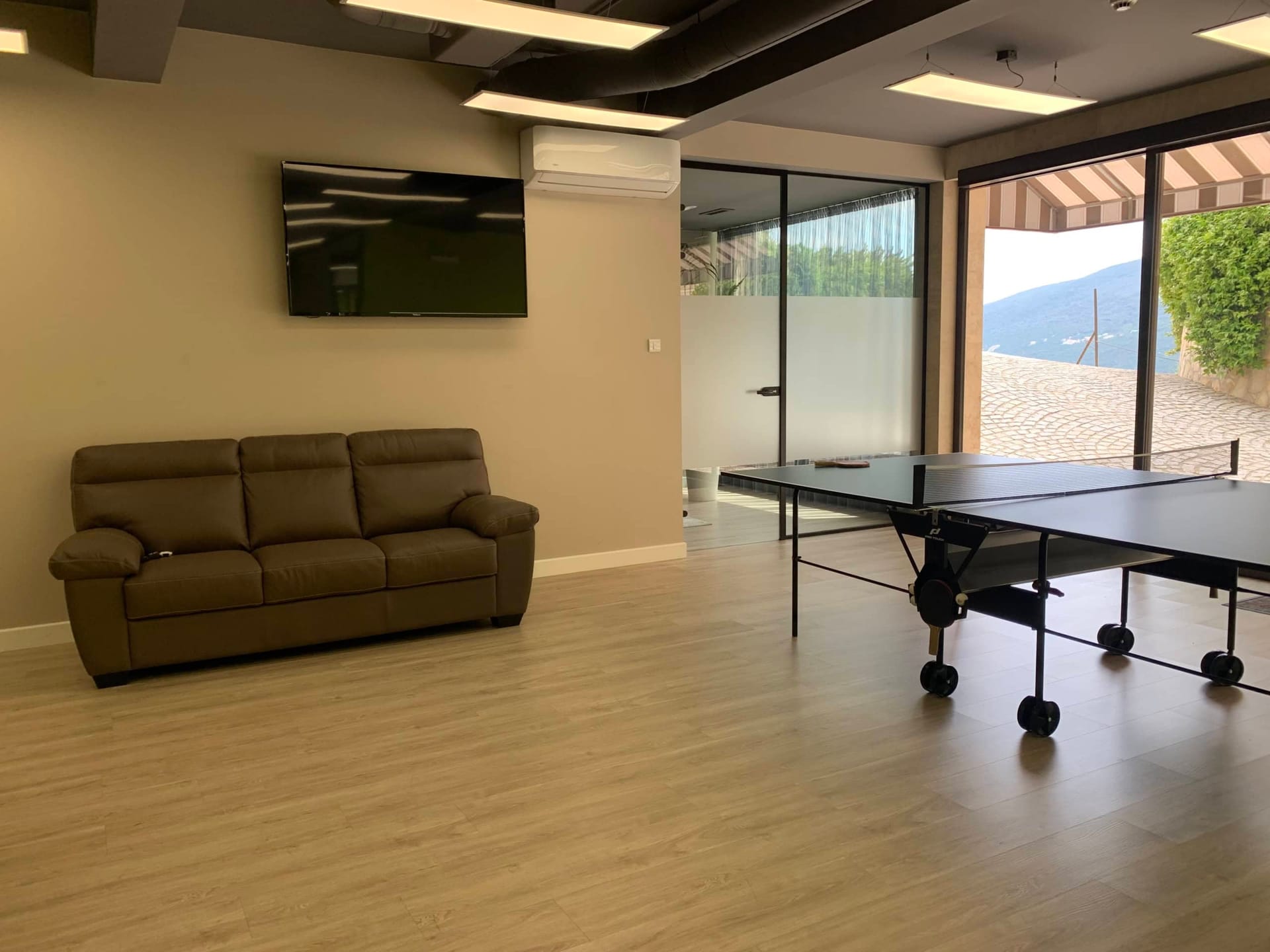 Igraonica sa stolom za stoni tenis i kaučem u stambenom kompleksu Kumbor, Crna Gora: moderan enterijer sa panoramskim pogledom.