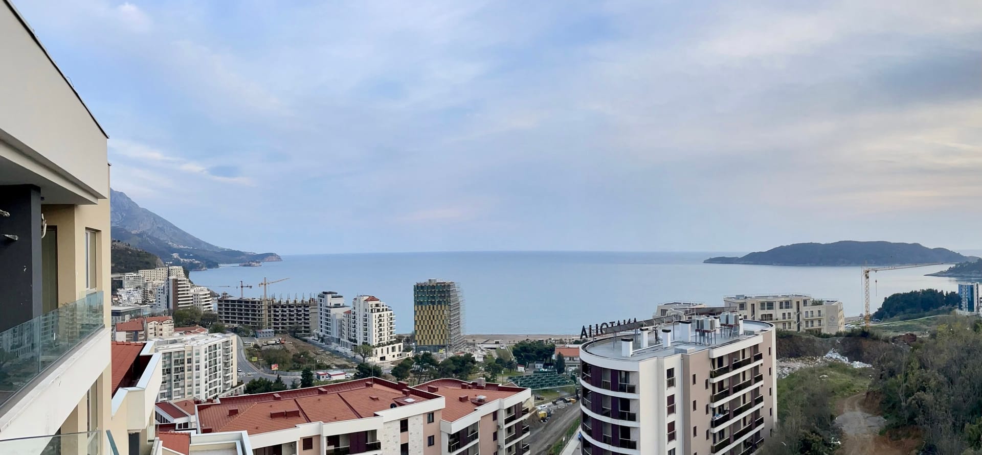 Panoramski pogled na more i grad Bečići, Crna Gora, sa balkona modernog stana u stambenom kompleksu.
