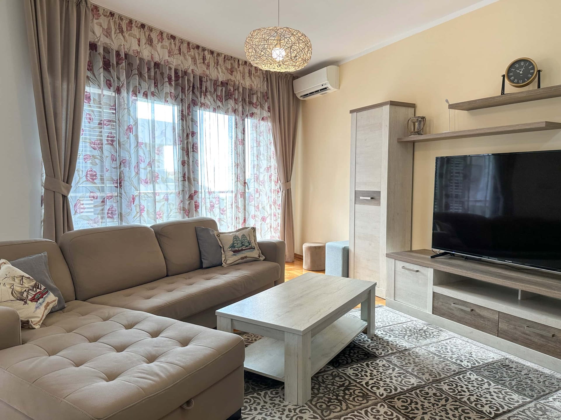 Udoban dnevni boravak sa bež sofom, TV zonom i panoramskim prozorima u stanu u Bečićima, Crna Gora.
