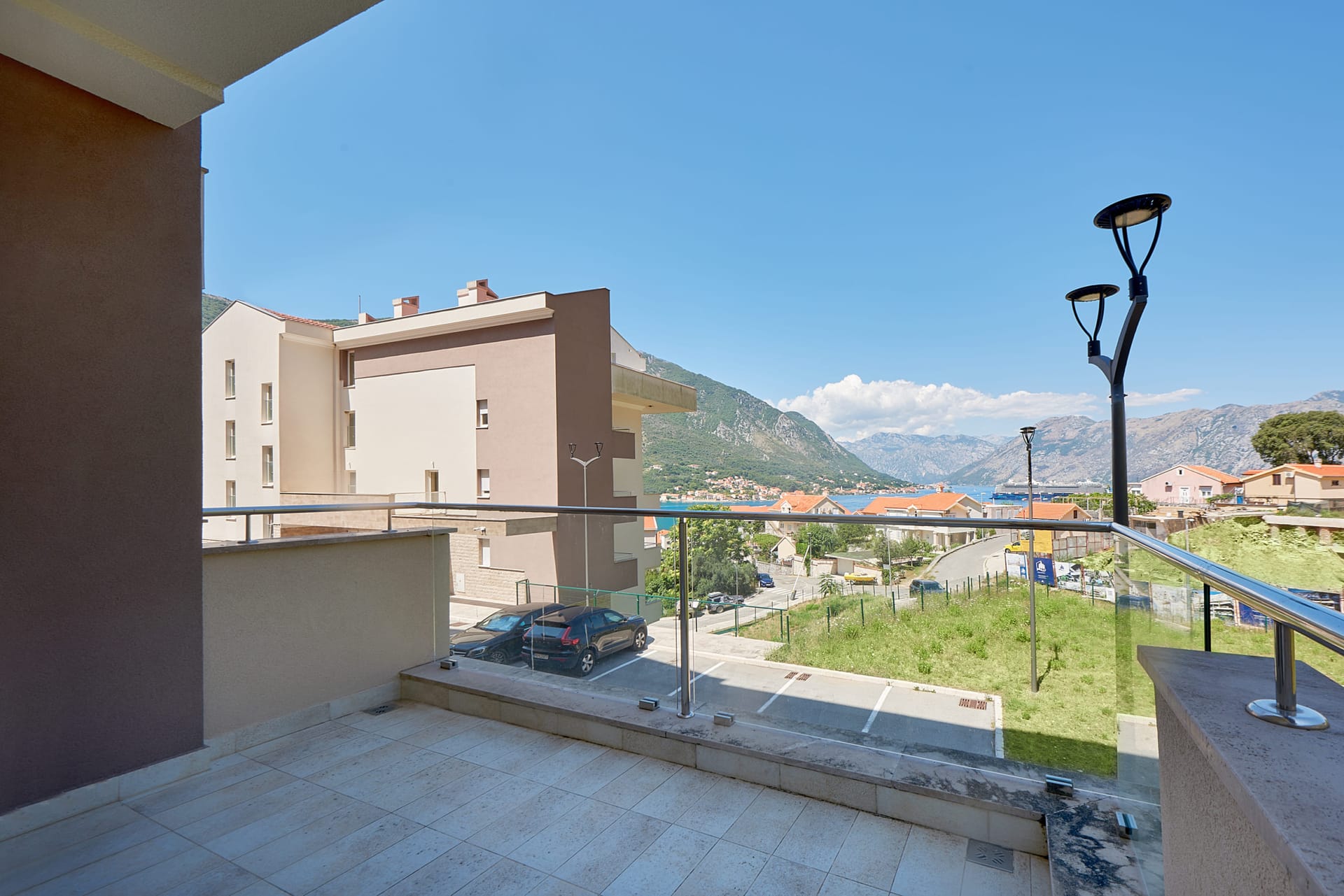 Pogled s balkona stana u Dobroti, Crna Gora: panorama Kotorskog zaliva, planina i savremene stambene izgradnje.