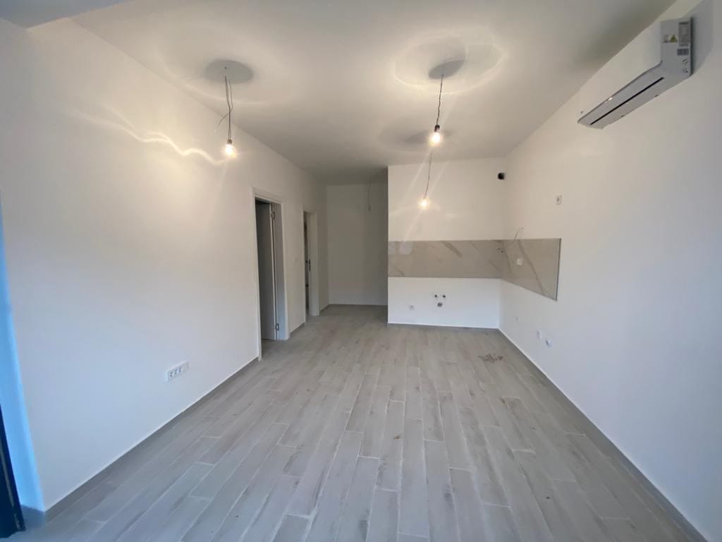 Svetao dnevni boravak sa kuhinjskim delom u novom stanu, Dobrota, Crna Gora: svetao pod, klima-uređaj, savremeno renoviranje.