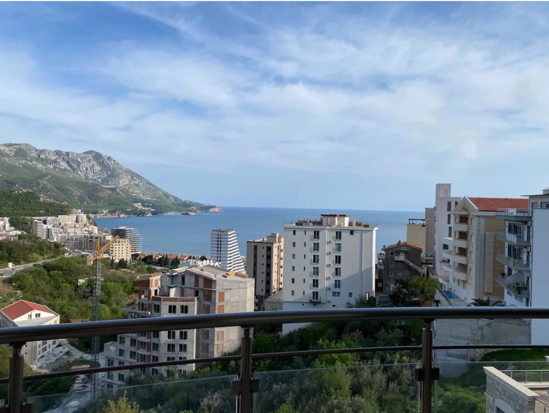 Panoramski pogled na more i planine sa balkona stana u Bečićima, Crna Gora, sa pogledom na gradsku izgradnju i obalu.