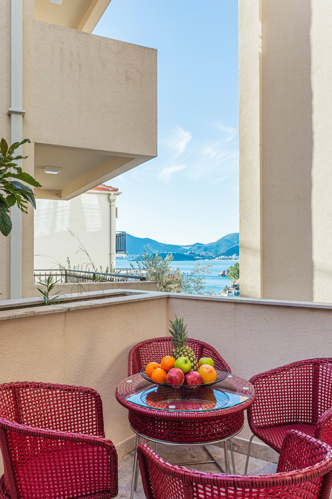 Balcony with red wicker furniture and a view of the sea and mountains in an apartment, Pržno, Montenegro.