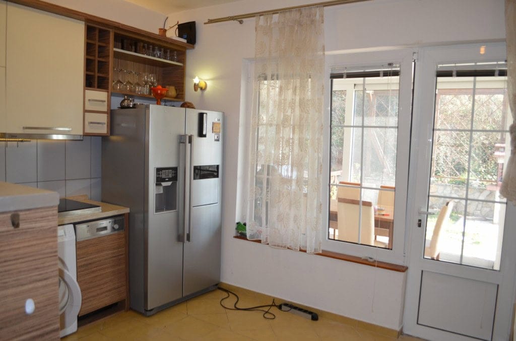 Kuhinja u apartmanima u Baru, Crna Gora: svetao nameštaj, veliki frižider i izlaz na terasu.