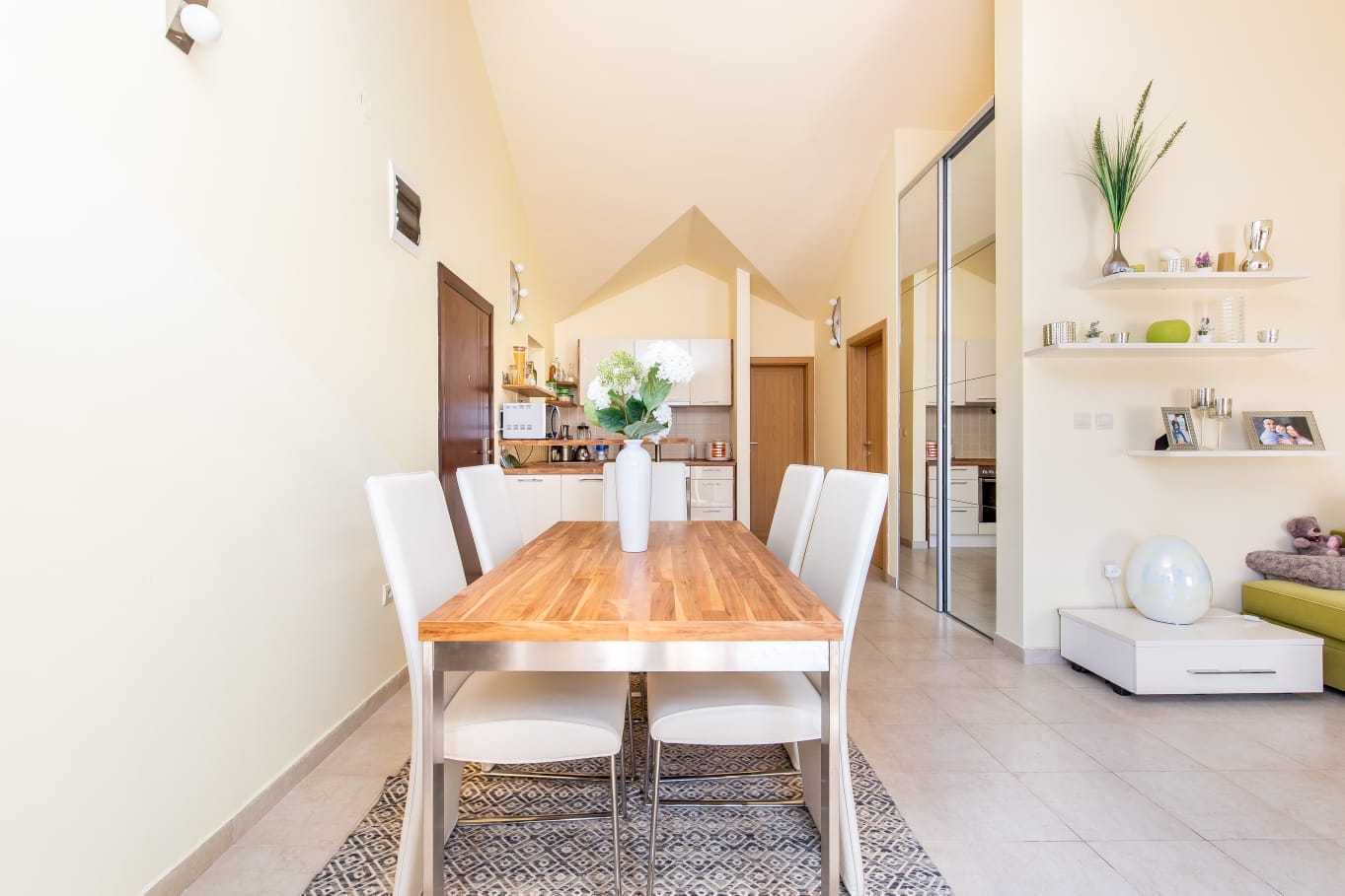 Helles Wohnzimmer mit Essbereich in einer Wohnung, Đenovići, Montenegro: Holztisch, weiße Stühle und Küche.