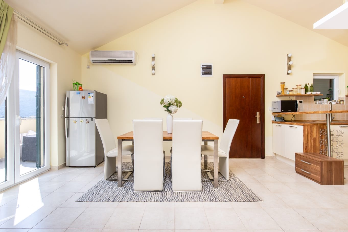 Helles Wohnzimmer mit Essbereich in einer Wohnung in Đenovići, Montenegro: moderne Küche, Möbel und Zugang zur Terrasse.