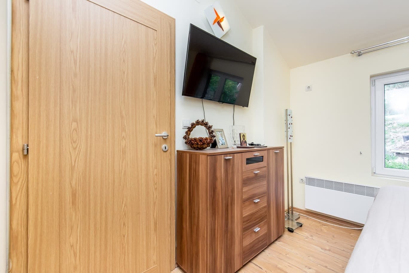 Schlafzimmer in einer Wohnung in Đenovići, Montenegro: Holzkommode, Wand-TV, helle Ausstattung und Blick aus dem Fenster.