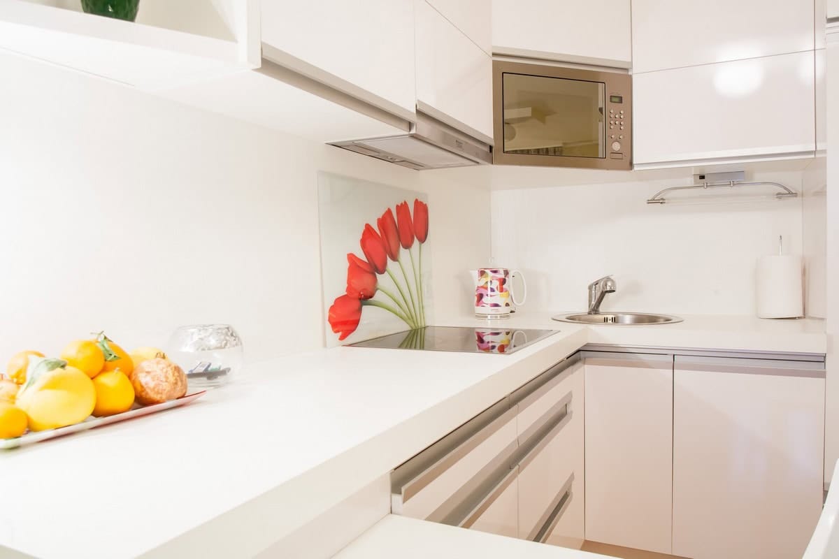 Savremena bela kuhinja u kući u Budvi, Crna Gora: ugradni uređaji, backsplash sa tulipanima i svetao enterijer.