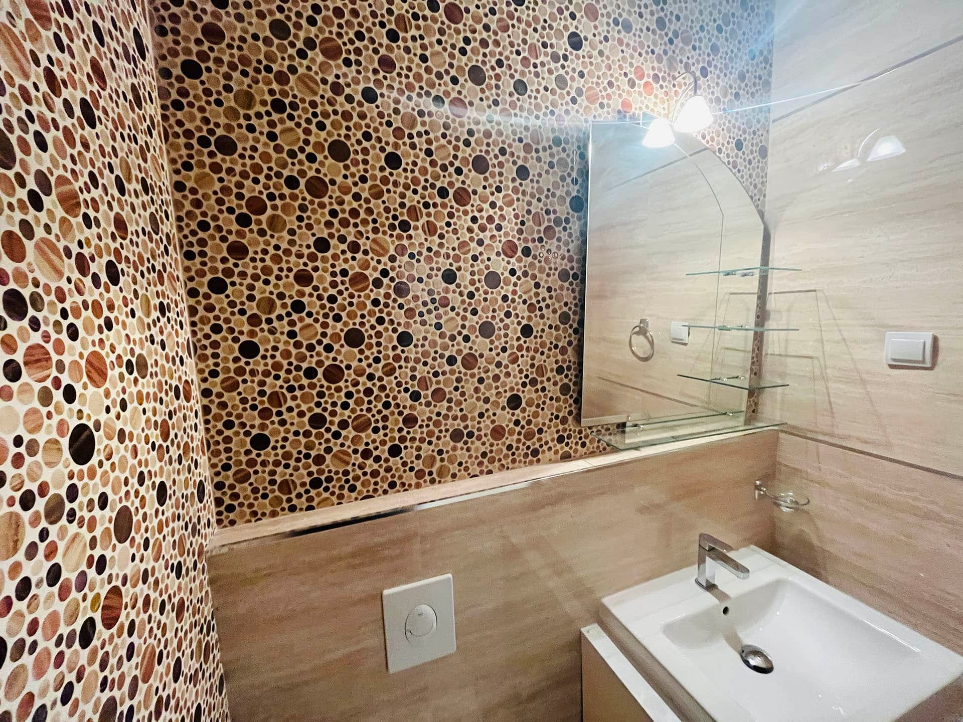 Karadağ, Budva’daki bir dairede modern banyo: mozaik fayans, ayna ve açık tonlarda sıhhi tesisat.