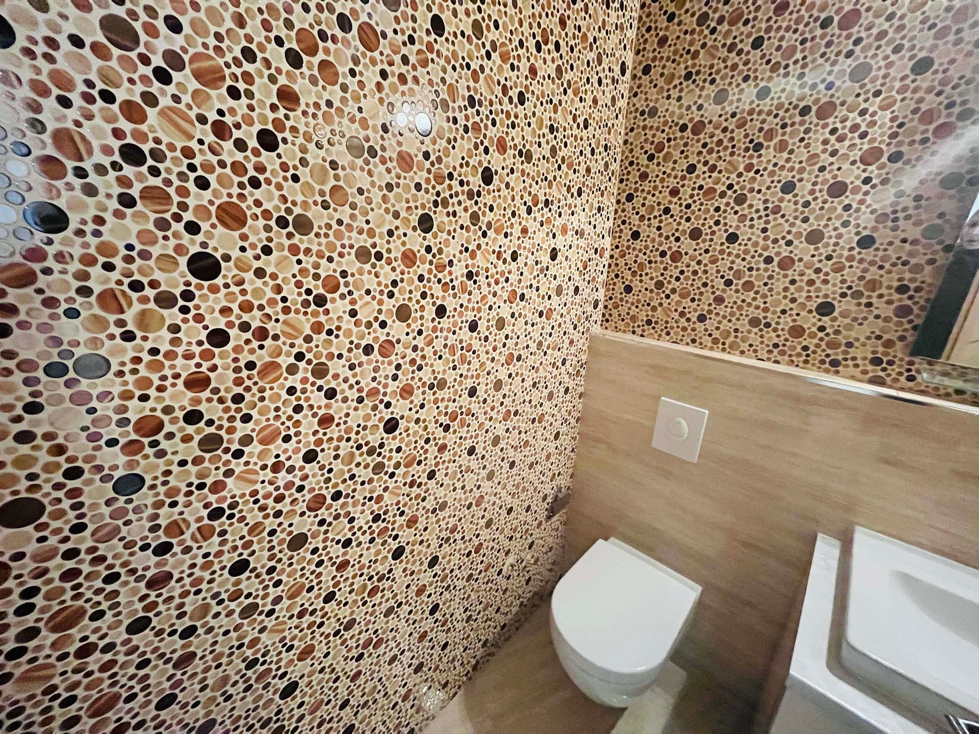 Karadağ, Budva’daki bir dairede modern banyo: duvarlar dairesel desenli mozaik fayansla kaplı.
