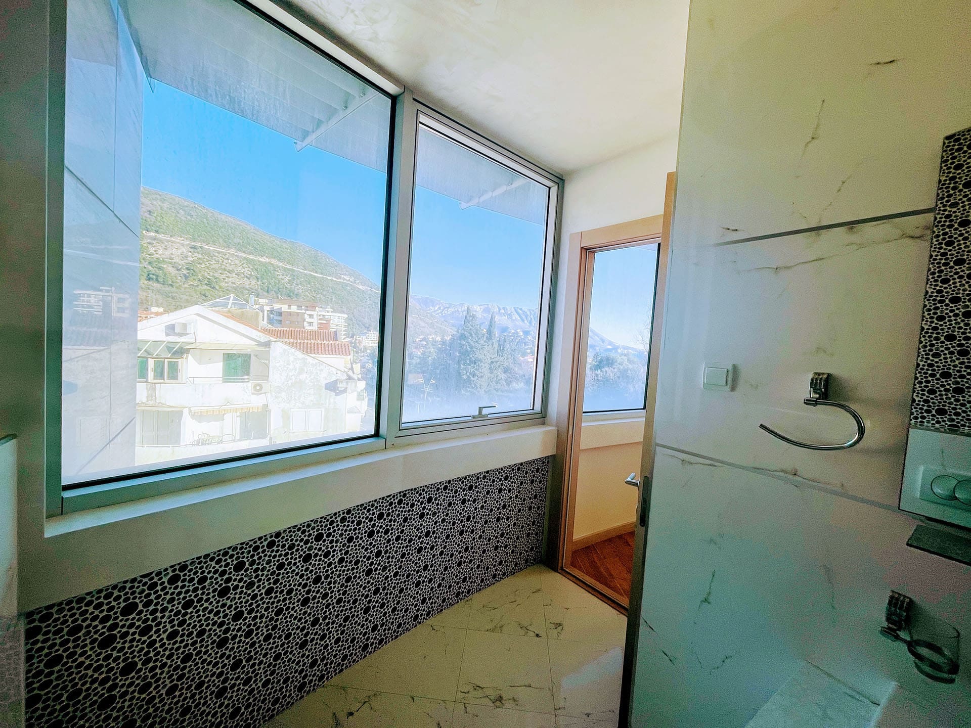 Budva, Karadağ’daki dairede dağ manzaralı panoramik pencereli banyo: modern fayans ve kaplama.