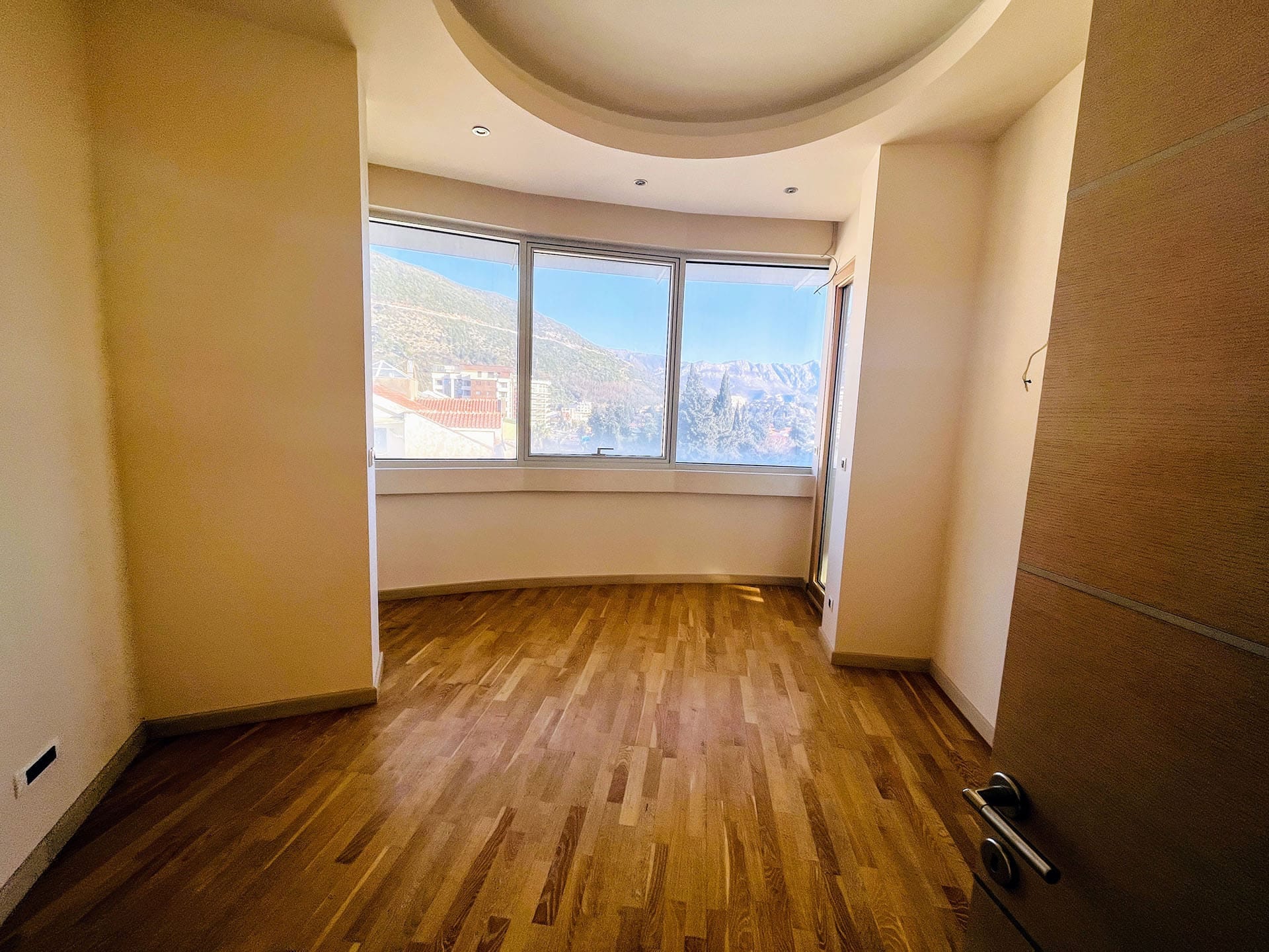 Parkeli ve dağların panoramik manzarasına sahip aydınlık oturma odası, Budva, Karadağ.