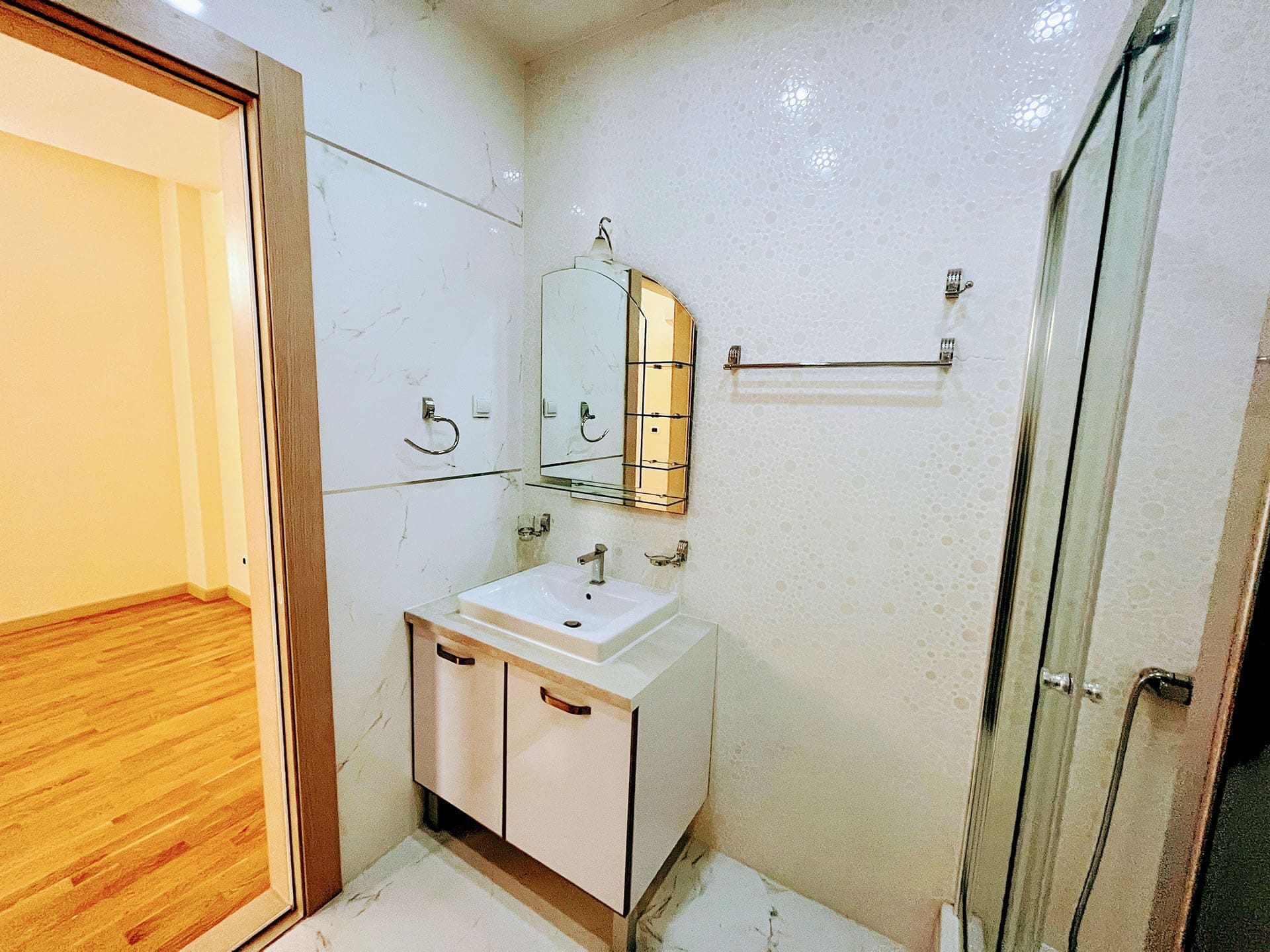 Budva, Karadağ’daki satılık dairede duş kabinli ve açık renkli kaplamalı modern banyo.