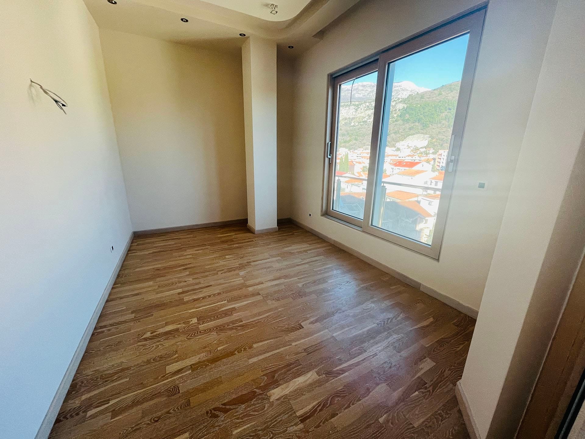 Parkeli ve dağlar ile şehrin panoramik manzarasına sahip aydınlık yatak odası, yeni dairede, Budva, Karadağ.