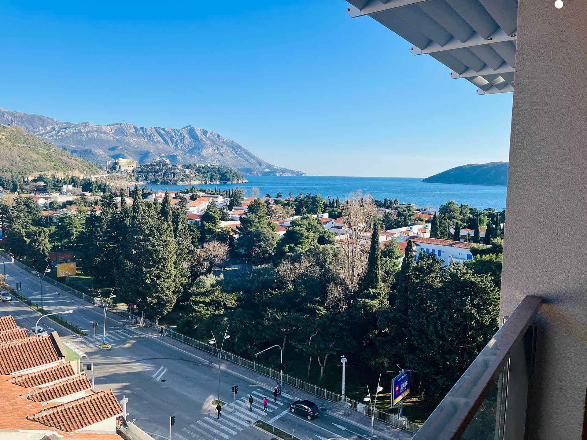 Karadağ, Budva’daki dairenin balkonundan panoramik manzara: deniz, dağlar, yeşil park ve şehir altyapısı.