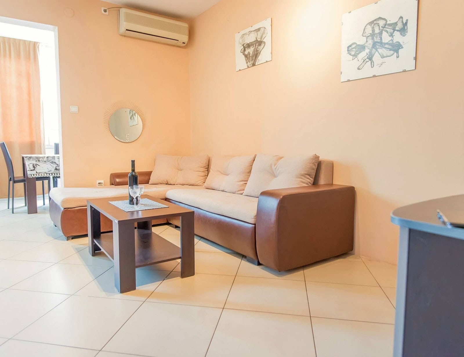 Cozy living room with an L-shaped sofa in an apartment in Dobrota, Montenegro: bright interior, air conditioner, and coffee table.