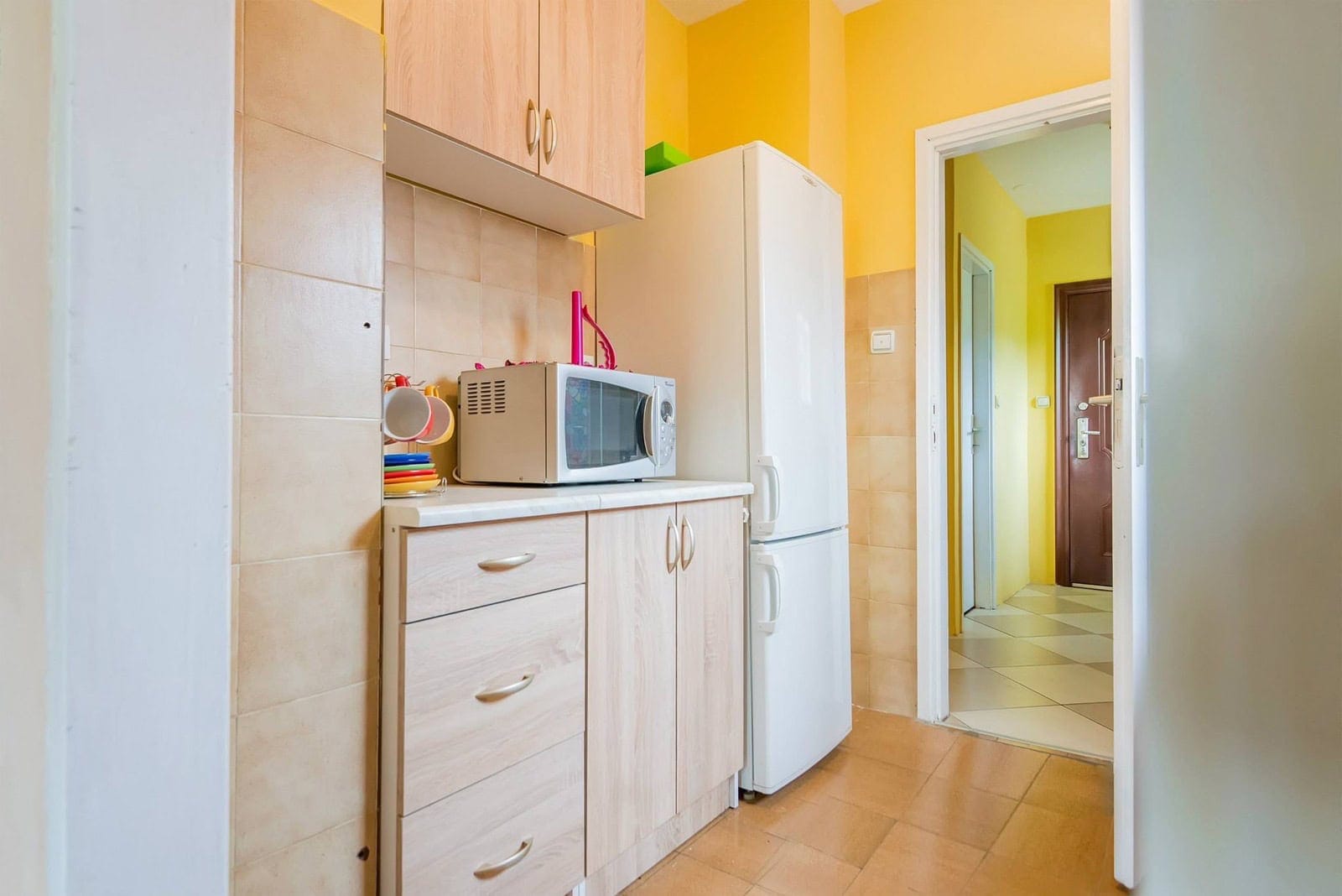 Compact kitchen with light-colored furniture and appliances in an apartment for sale, Dobrota, Montenegro.