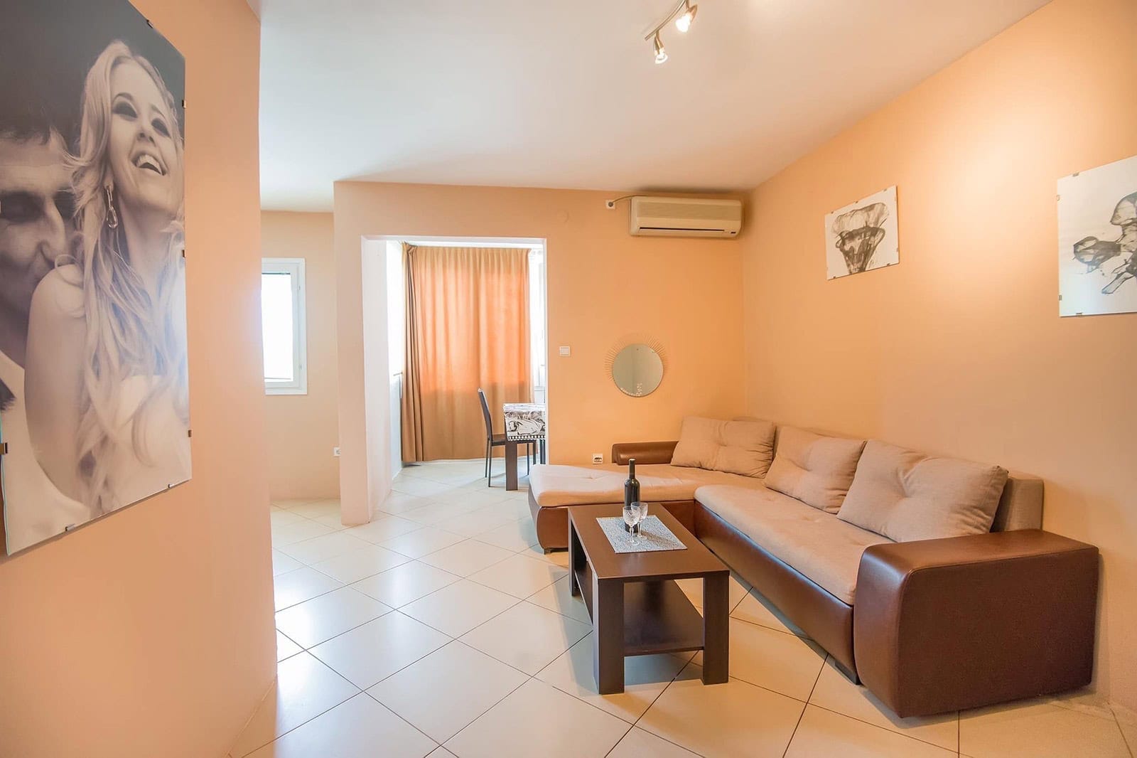 Living room with an L-shaped sofa and dining area in an apartment, Dobrota, Montenegro. Bright interior with tile flooring.