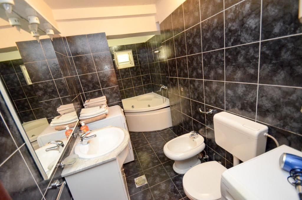 Bathroom with a corner bathtub and dark tiles in a house for sale in Kotor, Montenegro.