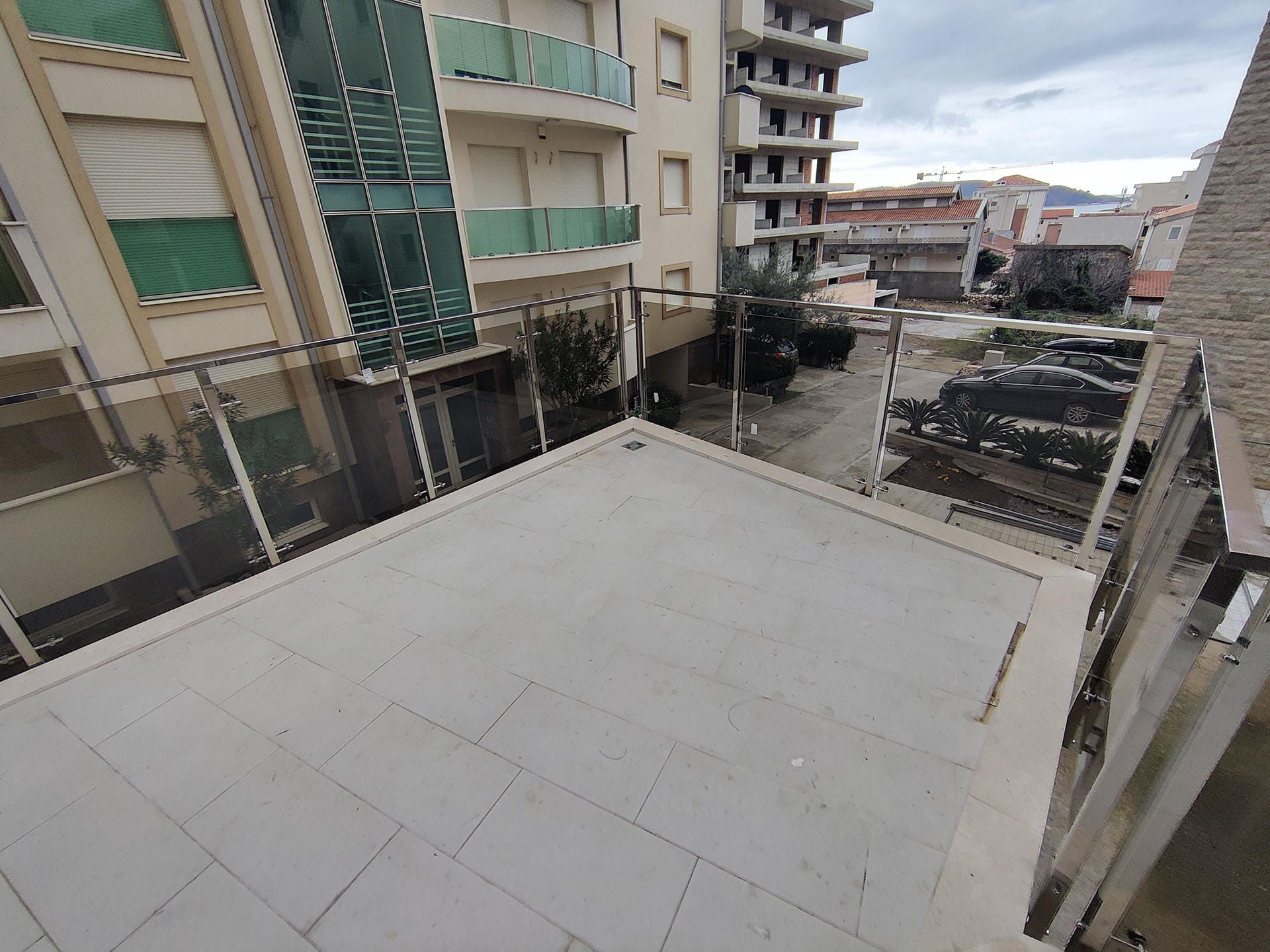 Prostrana otvorena terasa sa staklenom ogradom u stanu, grad Bečići, Crna Gora.