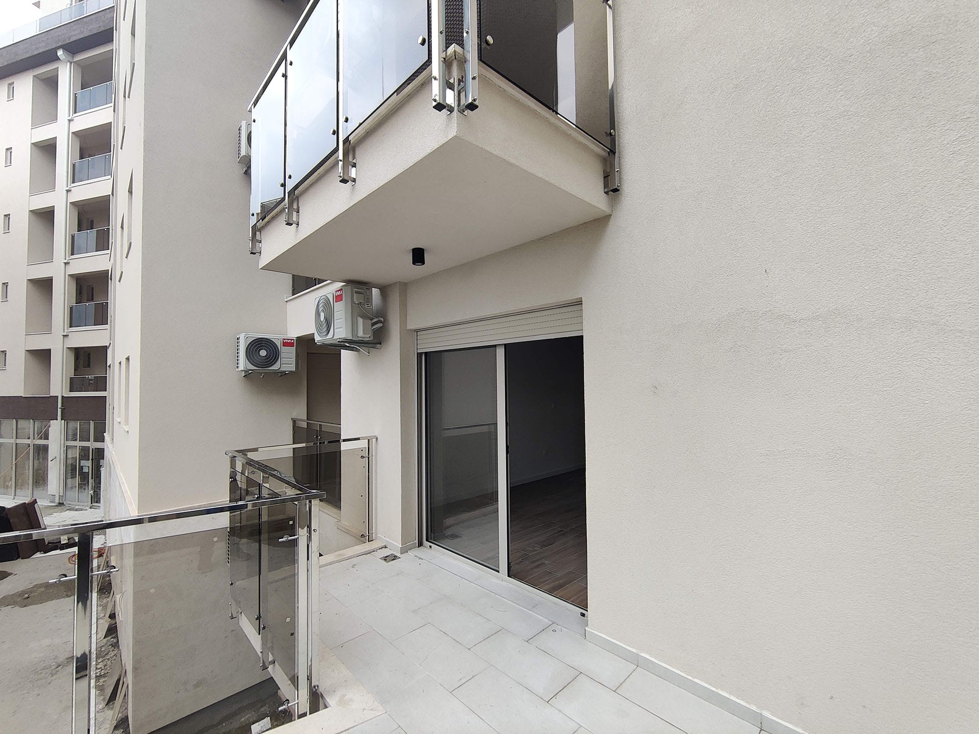 Balkon savremenog stana u Bečićima, Crna Gora: staklene ograde, svetla završna obrada i spoljne jedinice klima-uređaja.