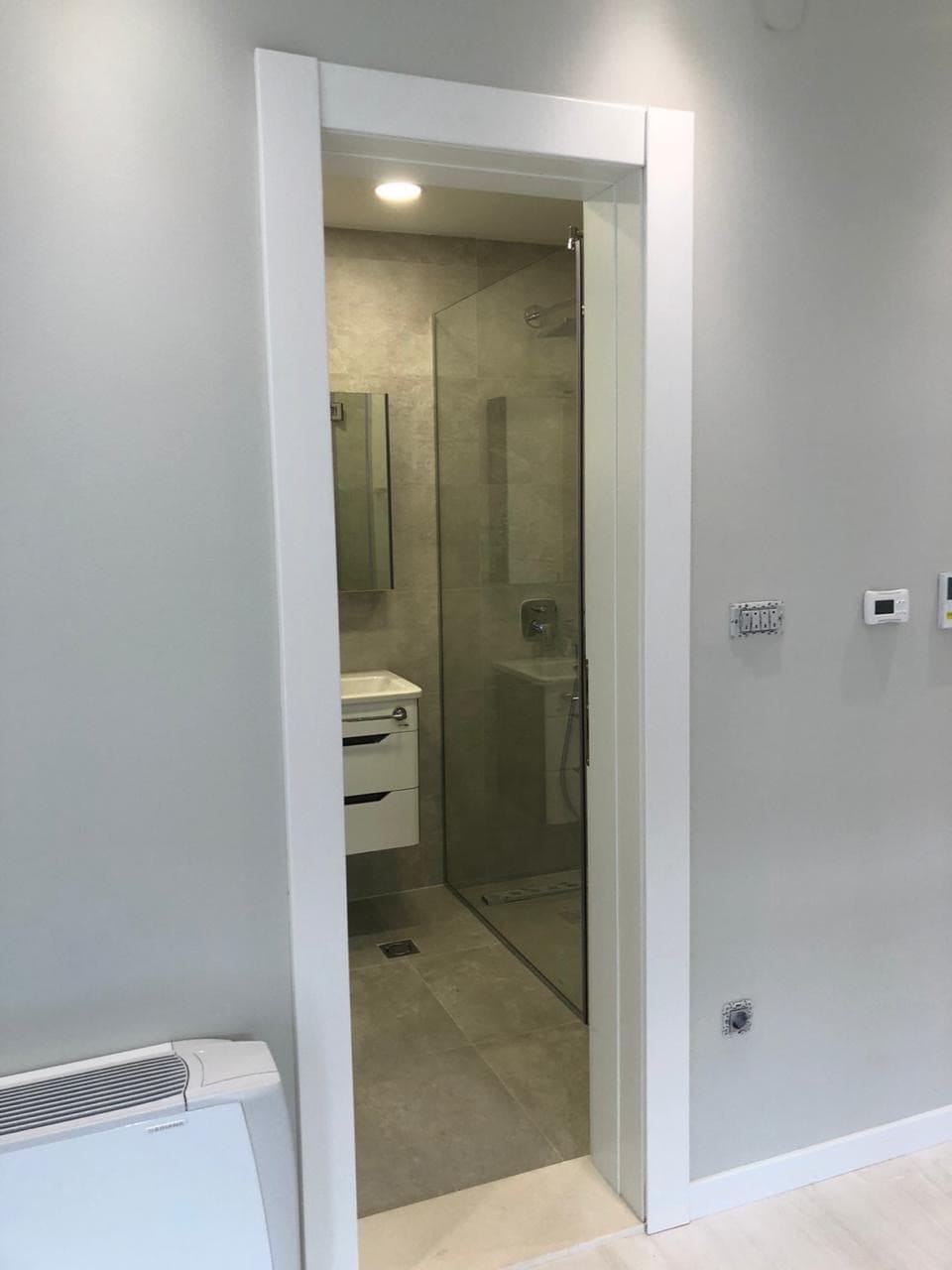 Savremeno kupatilo sa tuš kabinom u stanu u Dobroti, Crna Gora: stilna završna obrada i sanitarije.