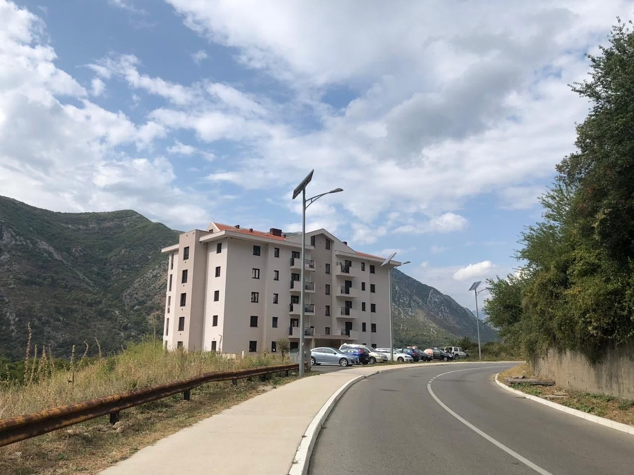 Savremena stambena zgrada u Dobroti, Crna Gora: pogled na zgradu sa parkingom u pozadini planina i slikovitog pejzaža.