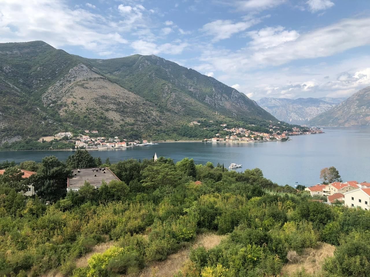 Panoramski pogled na Bokokotorski zaliv i planine iz stana u Dobroti, Crna Gora: priroda, more i priobalna gradnja.