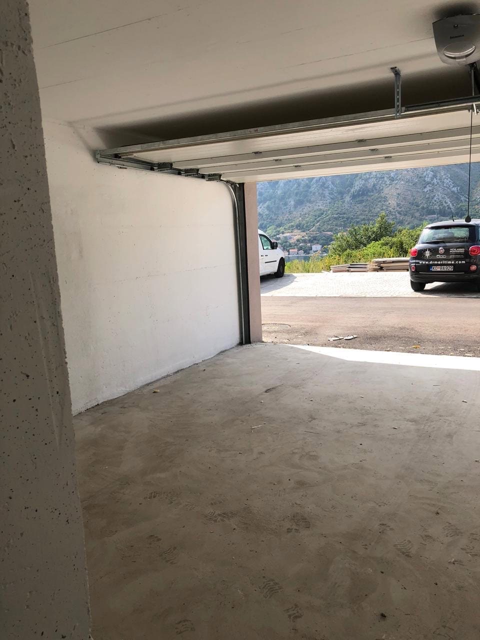 Prostrana garaža sa podiznim vratima u stambenom kompleksu, Dobrota, Crna Gora, pogled na planine i more.