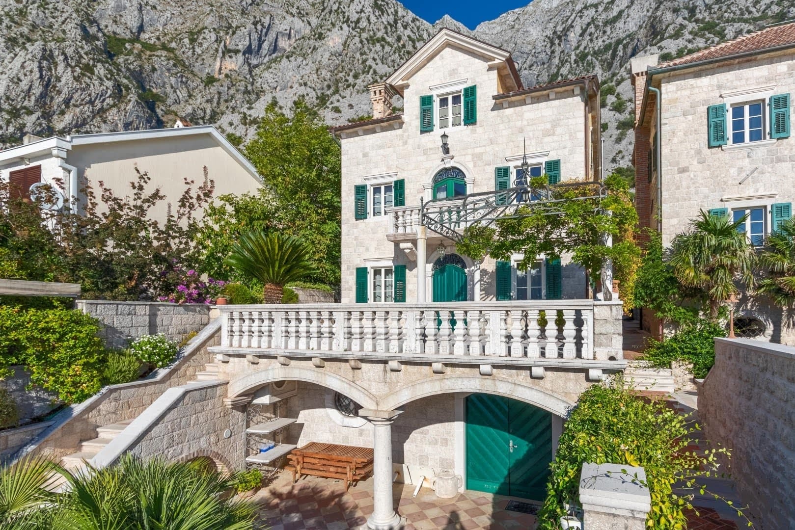 Kamena vila u mediteranskom stilu sa terasom i zelenim kapcima u naselju Ljuta, Crna Gora, u pozadini planine.