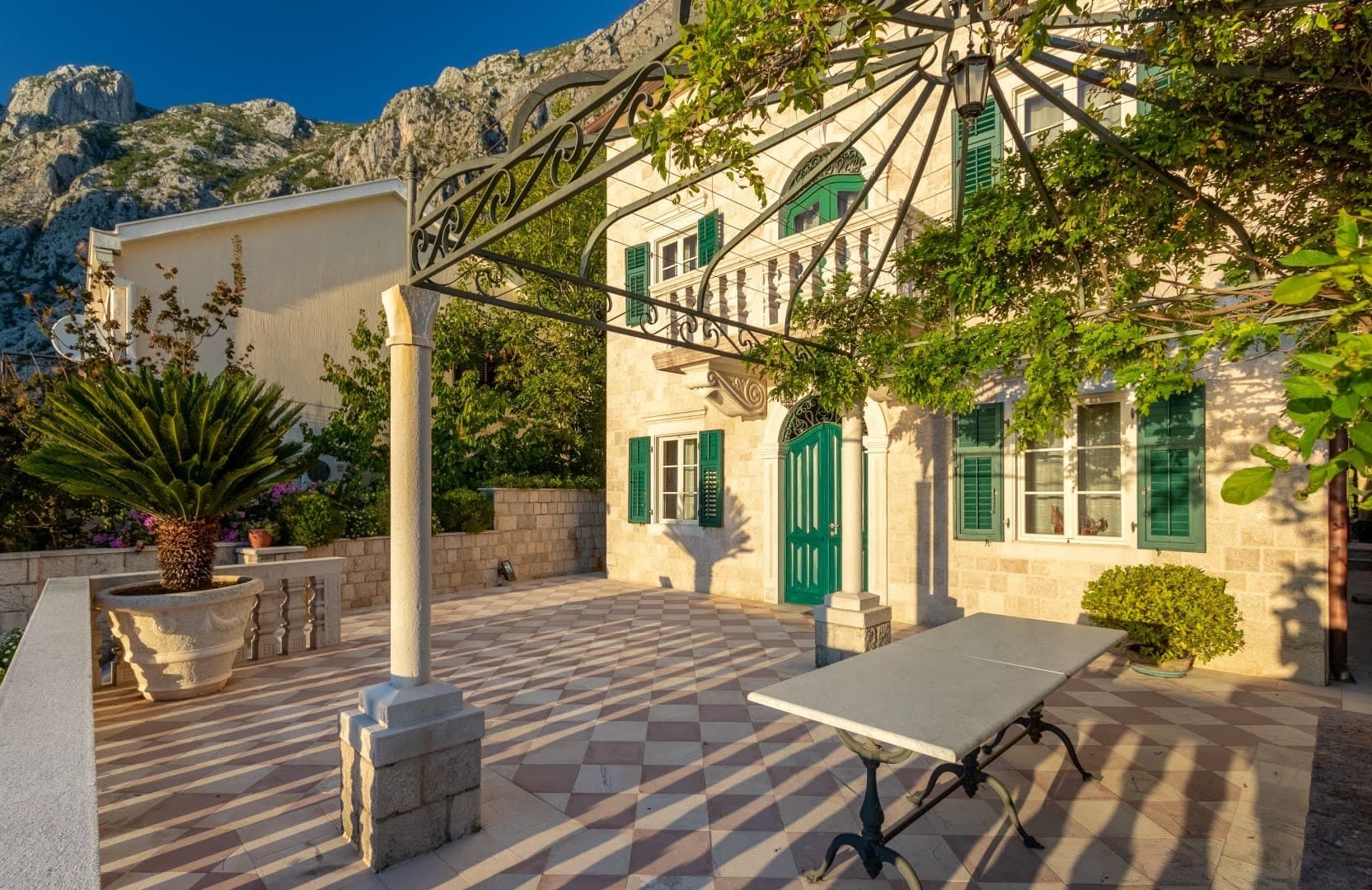 Kamena vila u Ljuti, Crna Gora: terasa s pergolom, mermerni sto i pogled na planine u mediteranskom stilu.