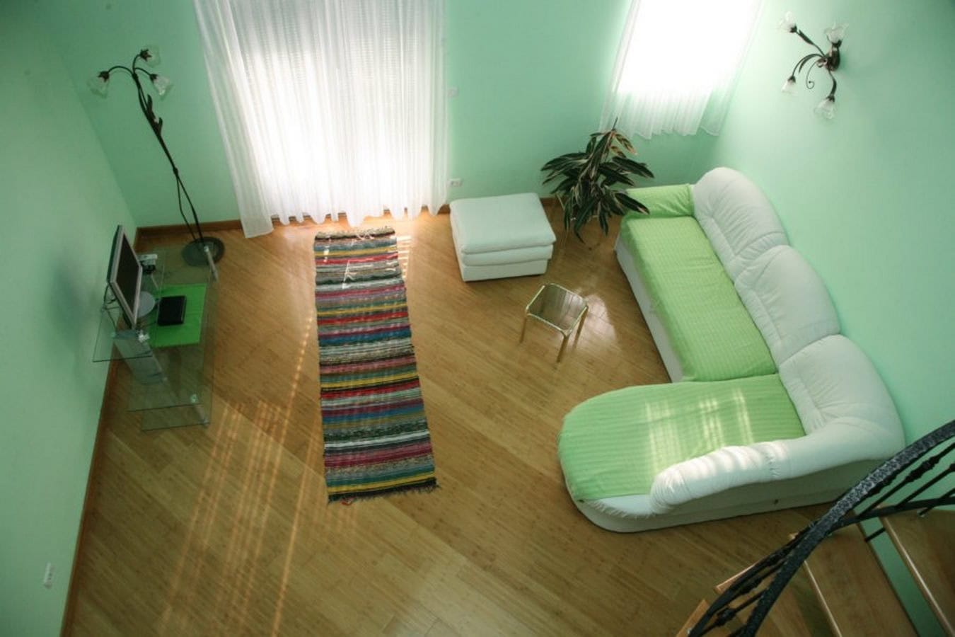 Helles Wohnzimmer mit grünen Wänden, weißem Sofa und Holzboden in einer Villa in Tivat, Montenegro.