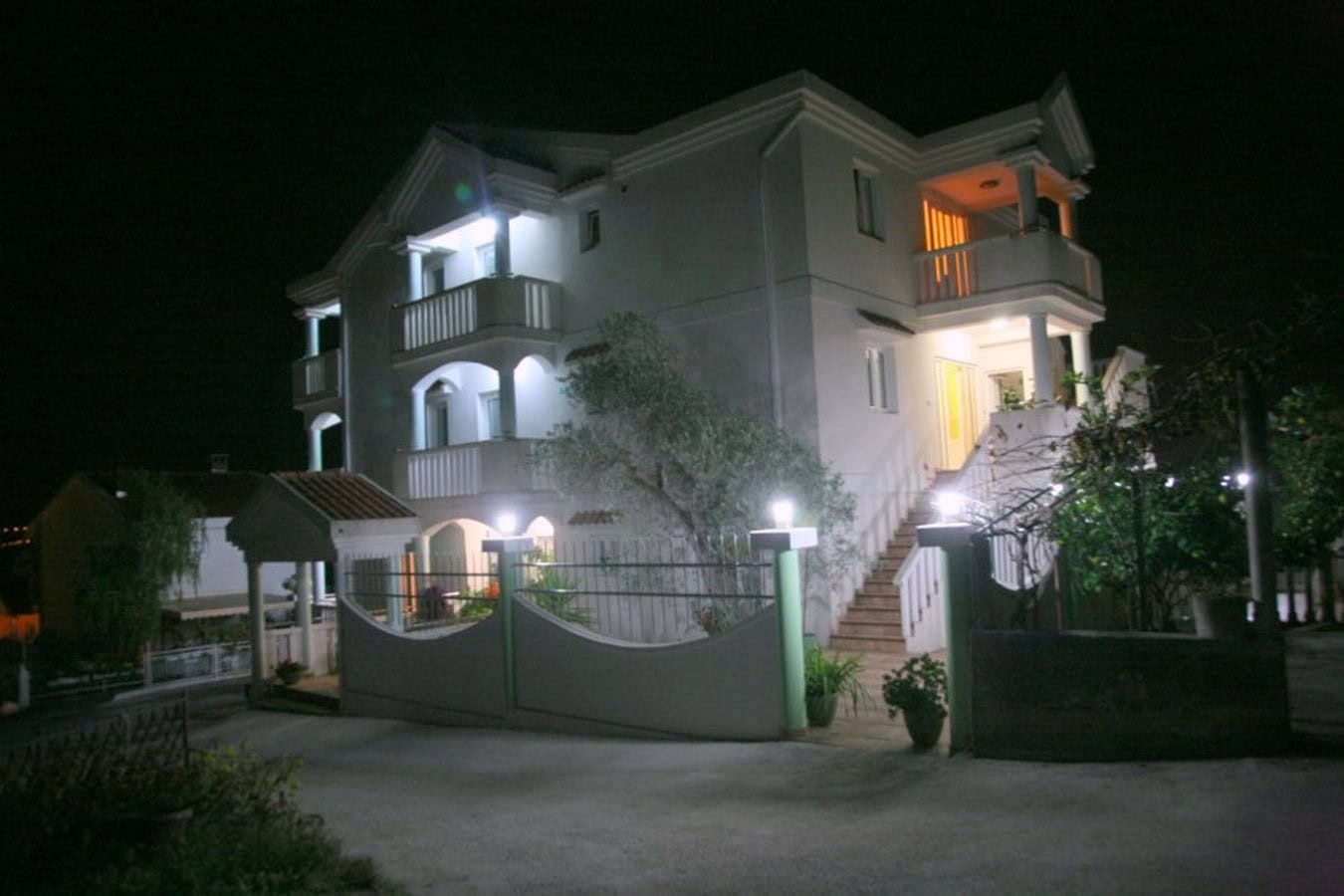 Dreistöckige Villa in Tivat, Montenegro: Fassade mit Beleuchtung, Balkonen und Treppe bei Nacht.