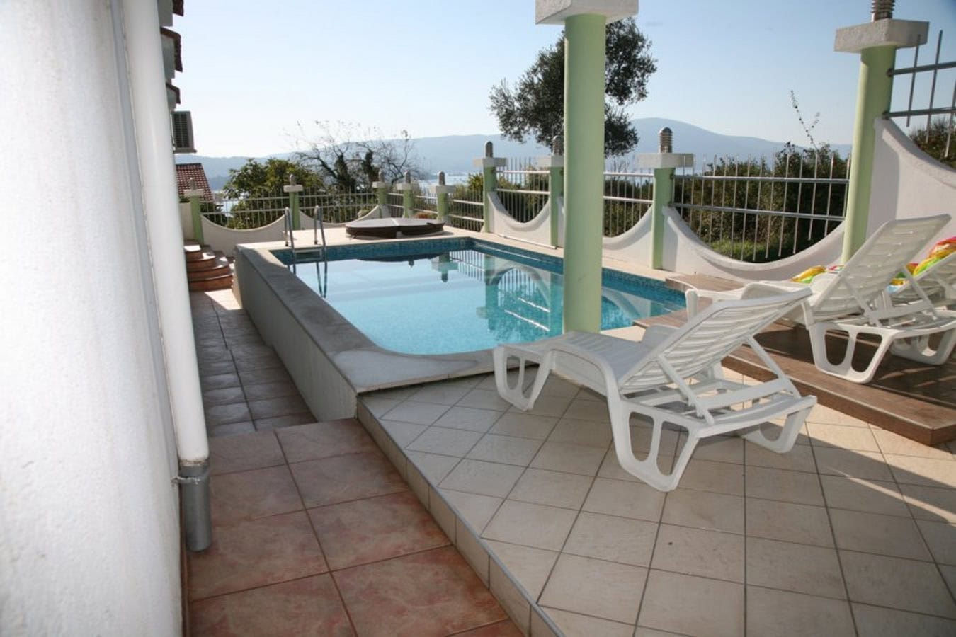 Offene Terrasse mit Pool und Liegestühlen in einer Villa in Tivat, Montenegro, mit Panoramablick auf das Meer und die Berge.