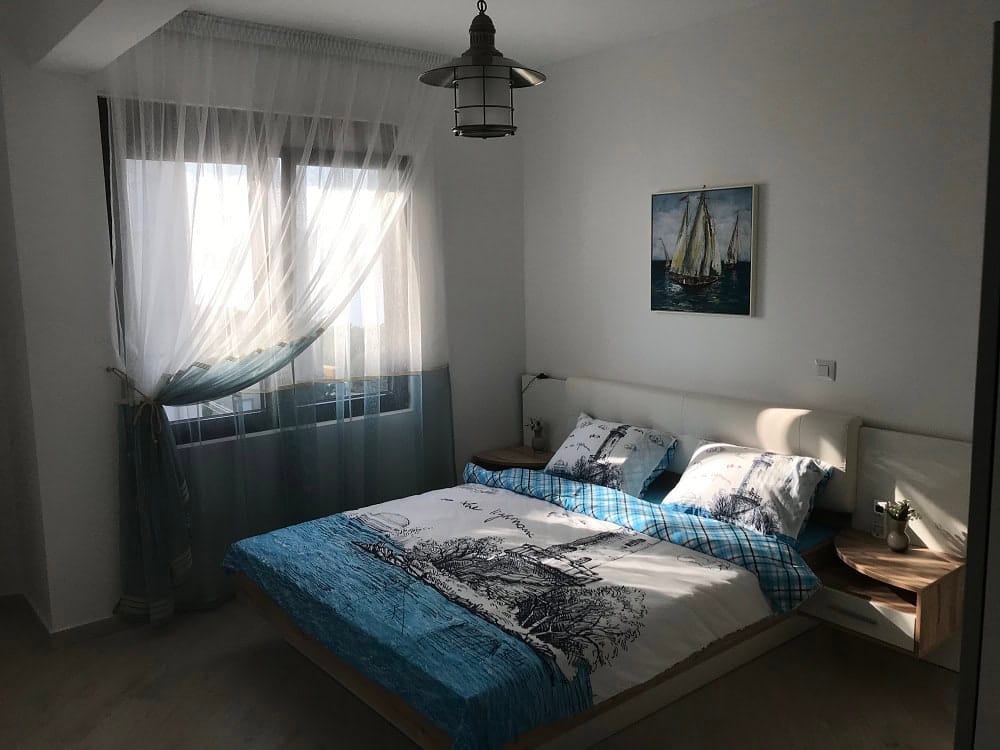 Helles Schlafzimmer mit Doppelbett in einer Wohnung, Dobri Vody, Montenegro: moderne Möbel und maritimes Dekor.