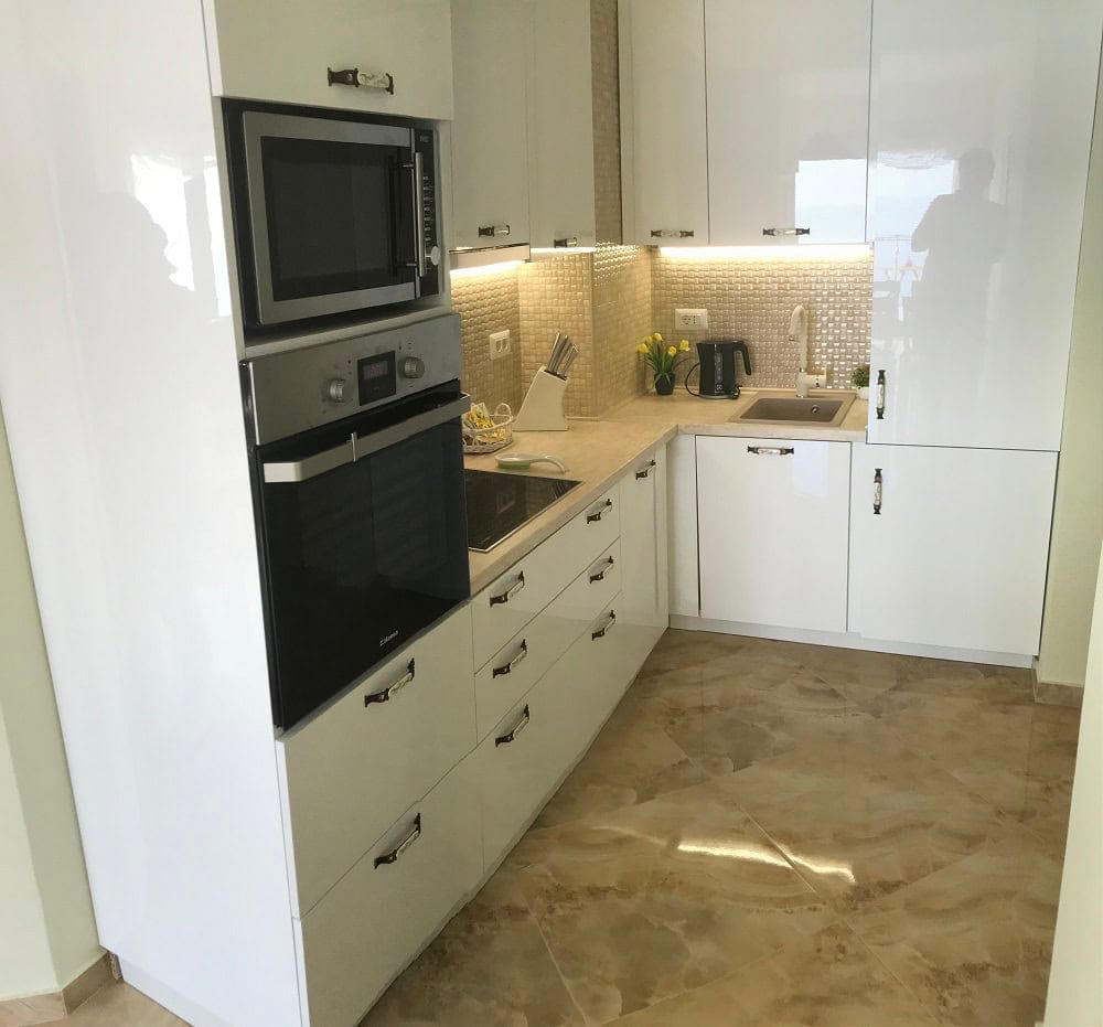 Moderne weiße Küche mit Hochglanzfronten und Einbaugeräten in einer Wohnung, Dobri Vody, Montenegro.