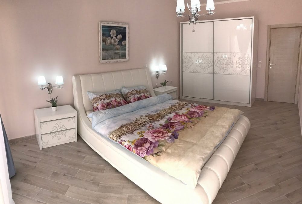 Helles Schlafzimmer mit weißem Bett und Einbauschrank in einer Wohnung in Dobri Vody, Montenegro. Modernes Interieur.