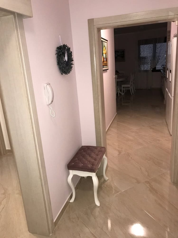 Flur mit weichem Pouf und heller Ausstattung in der Wohnung, Stadt Dobri Vody, Montenegro. Blick auf das Wohnzimmer mit Fliesen.