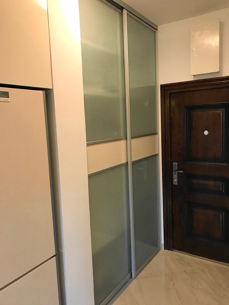 Built-in sliding wardrobe with frosted glass and a dark entrance door in a modern apartment, Dobri Vody, Montenegro.