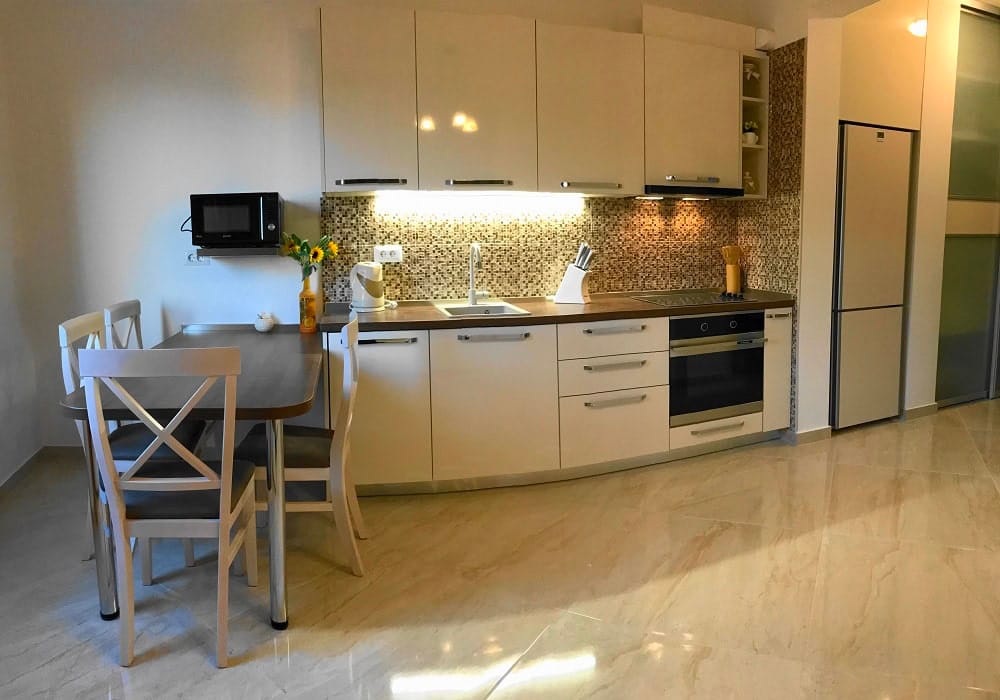 Modern kitchen with light cabinetry and dining area in an apartment, Dobri Vody, Montenegro.
