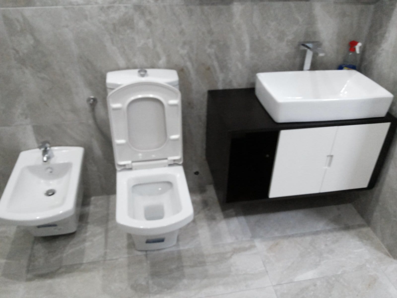 Savremeno kupatilo u kući u Baru, Crna Gora: sanitarije, bide i ormarić sa nadgradnim umivaonikom u završnoj obradi od kamena.
