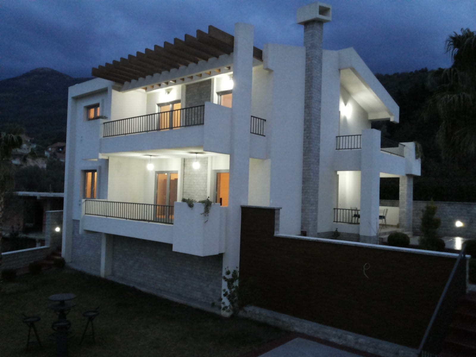 Savremena vila sa terasama i osvetljenjem u večernjim satima, Bar, Crna Gora. Fasada kuće sa kamenim oblogama.