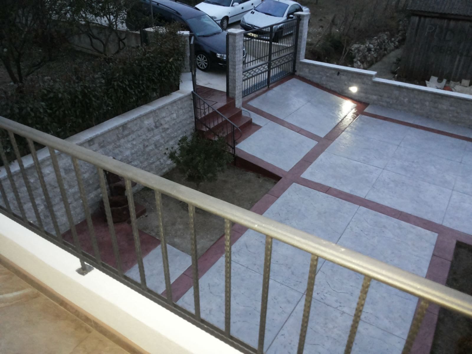 Pogled sa balkona na popločan parking i ograđeno dvorište privatne kuće u gradu Bar, Crna Gora.