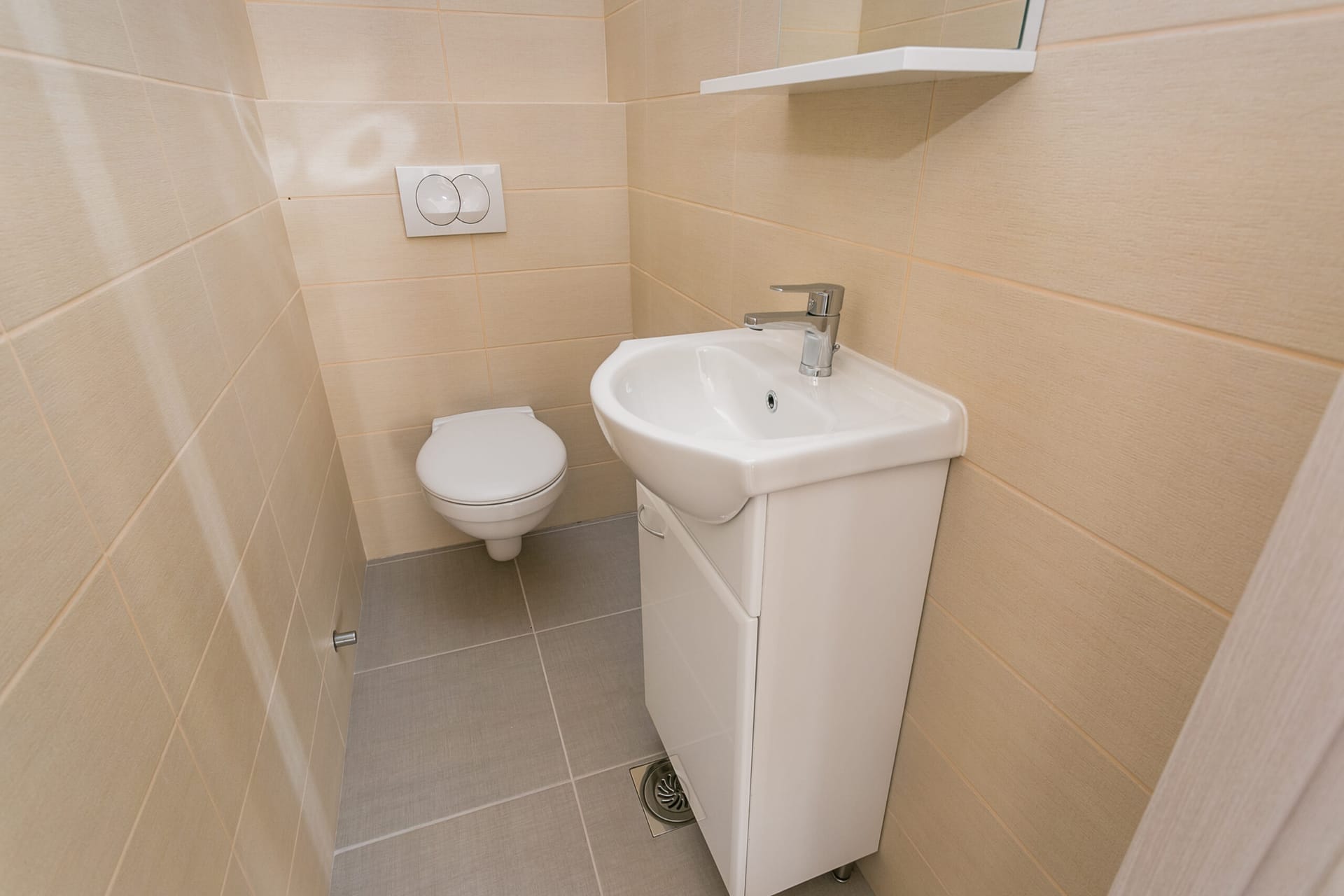 Savremeno kupatilo sa belom sanitarnom opremom i bež pločicama u penthausu, Rafailovići, Crna Gora.